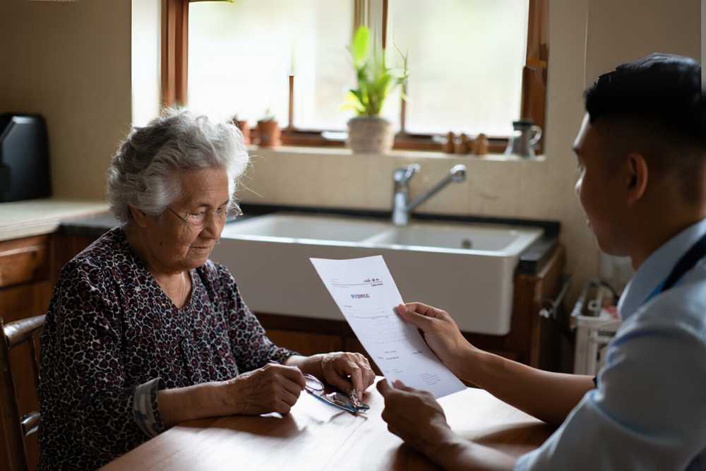 Prestataire de services à la personne expliquant une facture à une cliente à son domicile.