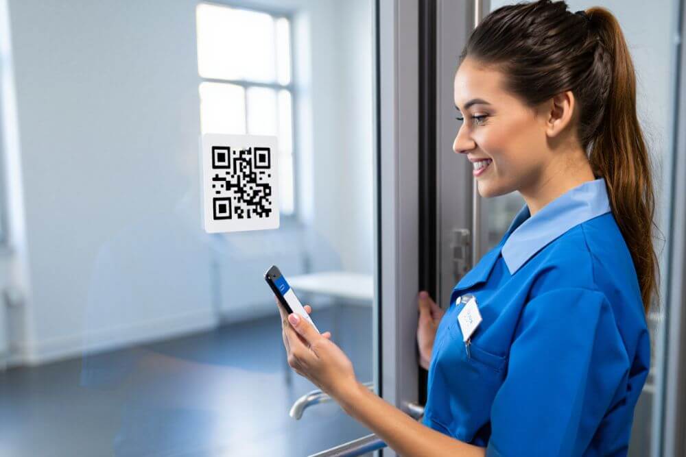 Agent d’entretien scannant un QR Code sur une porte avec son smartphone via SoftySoft Scanner.