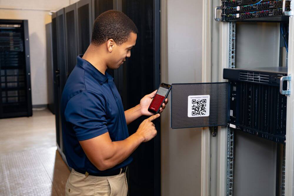 Technicien informatique pointant un QR Code dans une salle serveur à l’aide de SoftySoft Scanner.